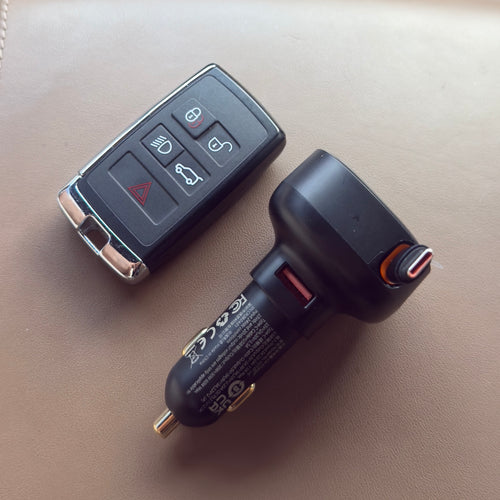 Dual USB-C car charger next to a modern car key on a leather surface