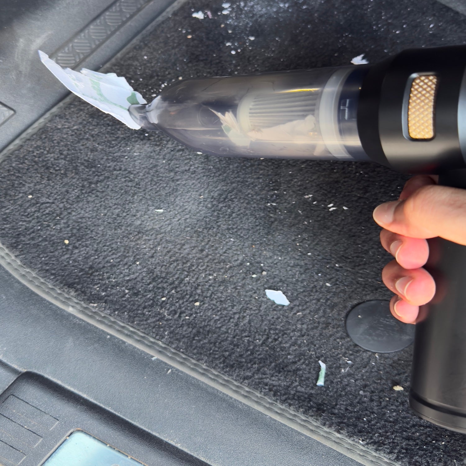 Cordless handheld car vacuum cleaning the driver's floor mat