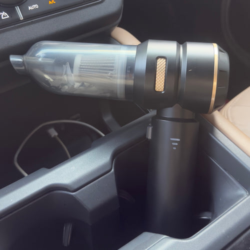 Cordless handheld car vacuum cleaner standing in a vehicle cup holder