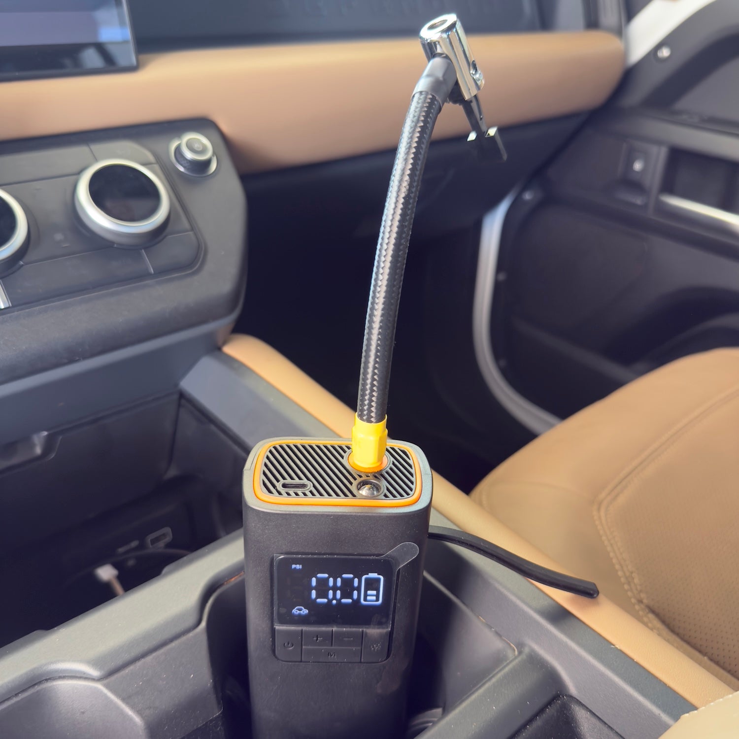 Portable cordless tire inflator with digital display connected to a car tire